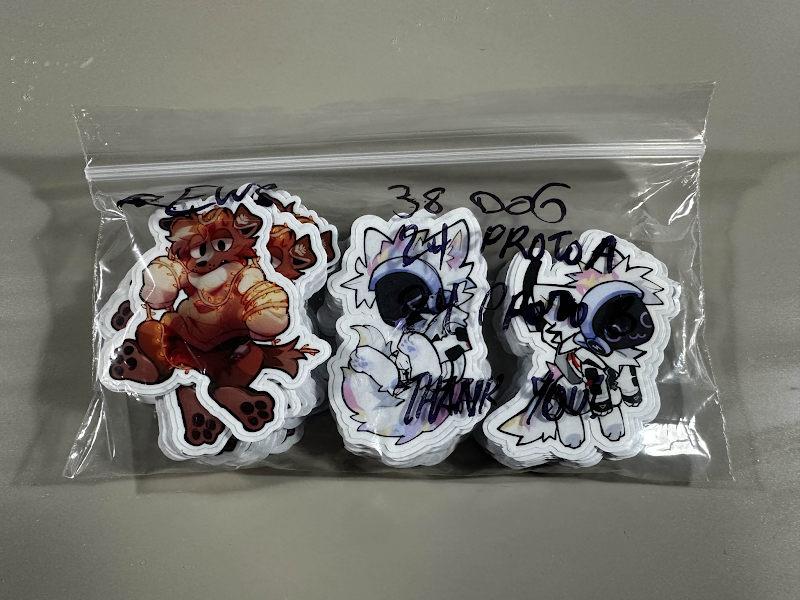 A bag holding three separate stacks of stickers, labeled for pickup.